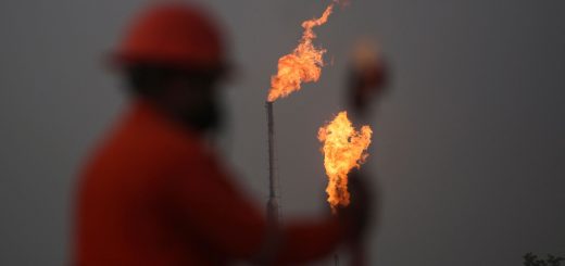 A worker takes measurements in front of gas flares at the state energy company Petroleos Mexicanos (Pemex) Perdiz Plant, which is unable to process the vast volumes of gas sent from the Ixachi field, outside of Tierra Blanca, Mexico May 4, 2022.