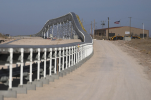 The Dune Express conveyor belt curving across flat West Texas terrain toward an Atlas Energy facility building.