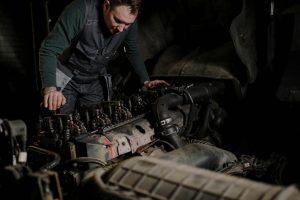 Mechanic focused on repairing a truck engine in an indoor workshop.