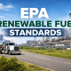 EPA renewable fuel standards hero image showing an American fuel tanker truck driving past fuel storage tanks and a refinery complex under a blue sky.
