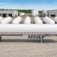 Illustrated wide aerial view of multiple white MC 331-style LPG cargo tank trailers lined up in an industrial yard, with warehouses and storage tanks in the background.