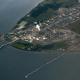 Aerial view of a waterfront refinery and storage tank complex illustrating how the global refinery crunch can affect refined product supply, fuel logistics, and downstream transportation markets.