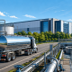 Water tank transport demand illustrated by a stainless steel tanker truck near water treatment infrastructure and a modern data center campus.