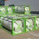 Rows of white OmniTAINER portable tanks in green Eurotainer intermodal frames outside an industrial building