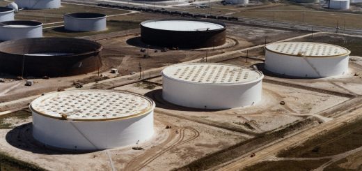 Aerial view of three large white crude-oil tanks among numerous cylindrical storage tanks and service roads near Nederland, Texas