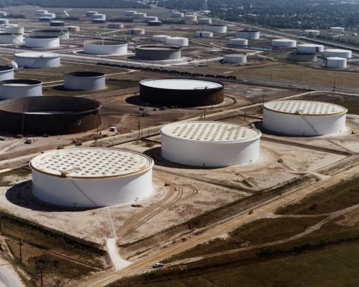 Aerial view of three large white crude-oil tanks among numerous cylindrical storage tanks and service roads near Nederland, Texas