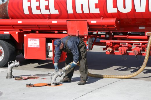 Tank-truck driver connects a fuel-delivery hose at a gasoline station.