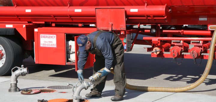 Tank-truck driver connects a fuel-delivery hose at a gasoline station.