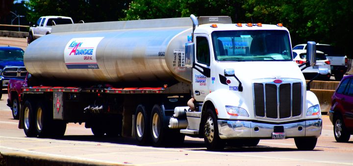 Silver gasoline tanker truck traveling on a divided interstate highway.