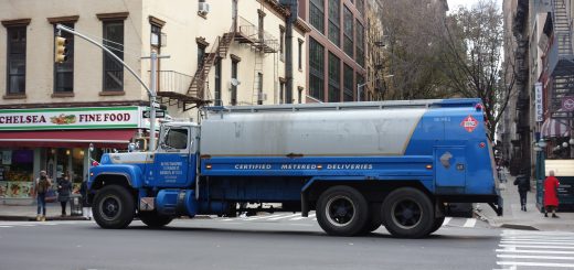 Blue and silver Mack fuel-delivery truck traveling along a Manhattan street.
