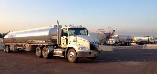 White American Fuels Mack tractor with a polished petroleum tank trailer parked in a fleet yard.