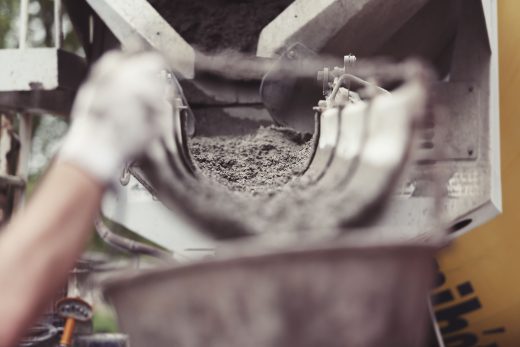 Wet concrete flowing down a mixer truck’s discharge chute.
Media title: Concrete Delivery and Construction Cost Pressure