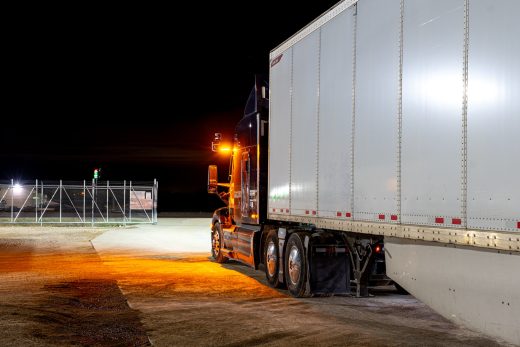 Amber cab-mounted warning beacon illuminated on an Aurora-equipped Peterbilt tractor at night.